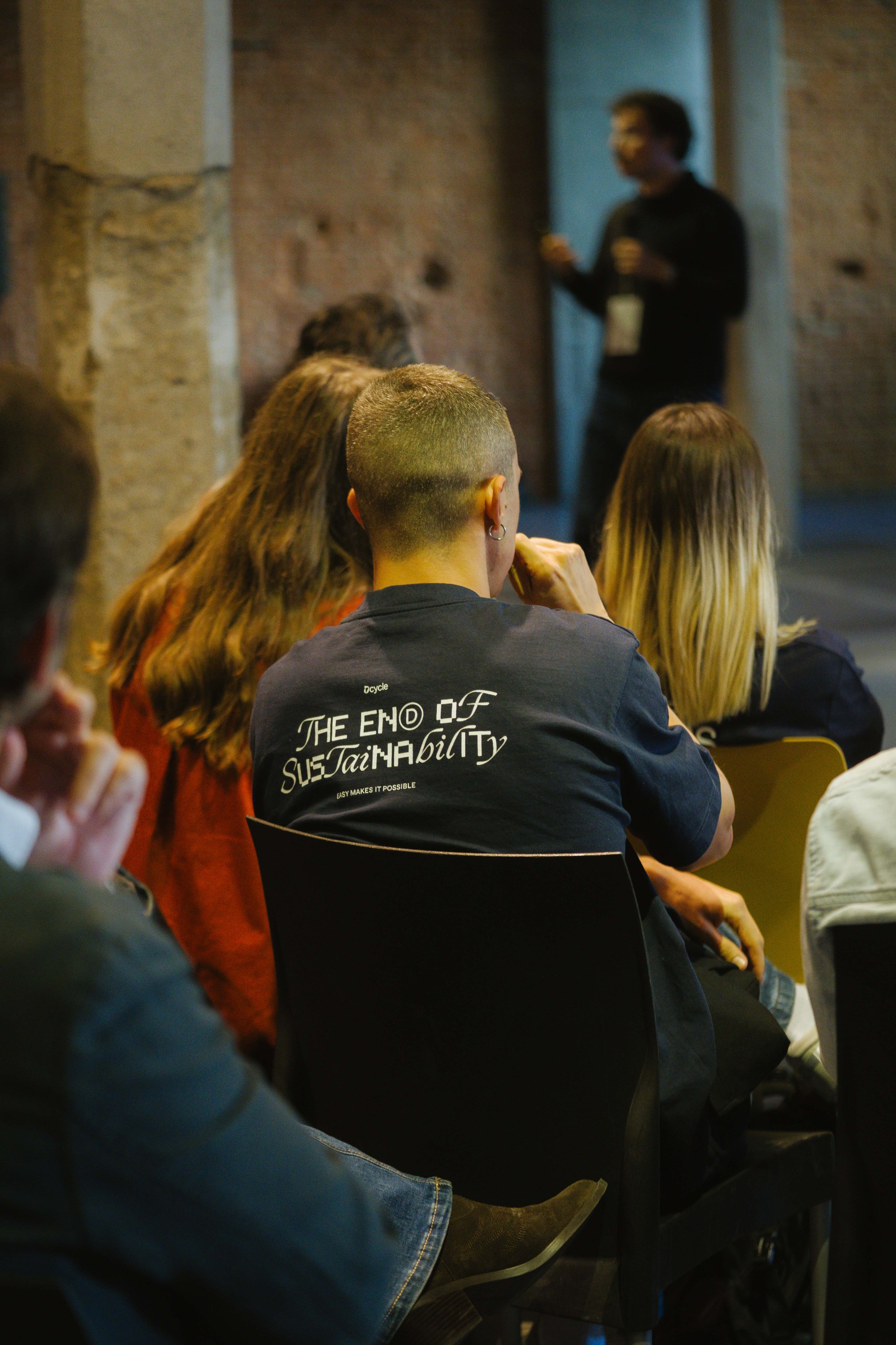 Attendee wearing Dcycle The End of Sustainability t-shirt watching the stage at Ahead Madrid